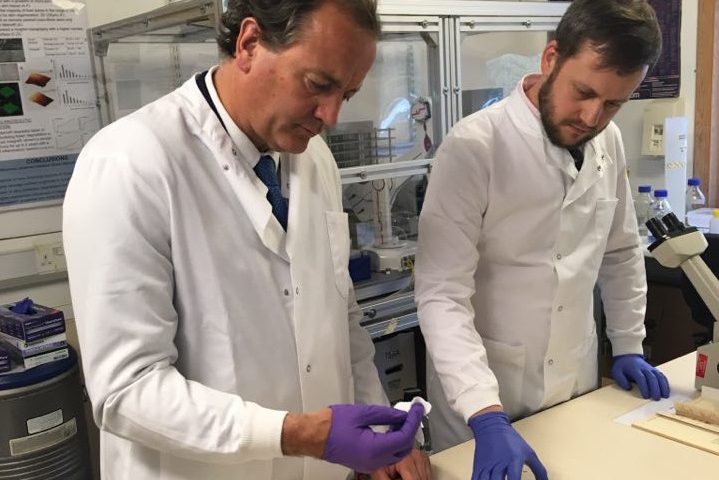 Scientist in White coat and gloves demonstrating a product to a visitor in the laboratory